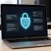 Ordinateur portable affichant une interface abstraite d’alerte de cybersécurité avec un cadenas numérique lumineux et des données anonymisées.